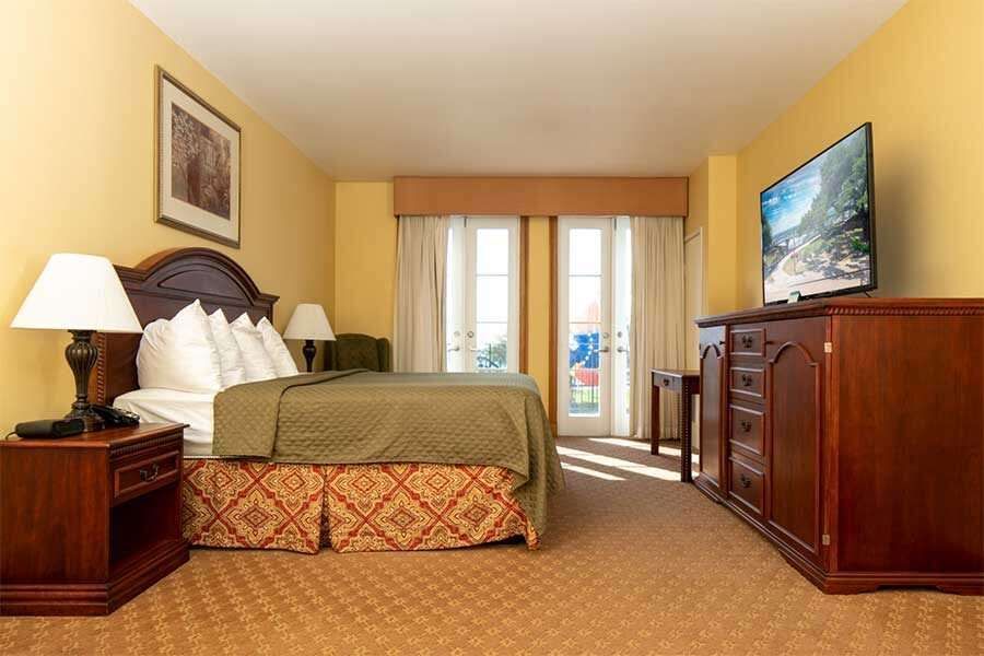 Hotel bedroom with a bed, television, and access to a balcony.