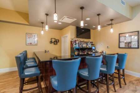 Bar with blue stools, dark counter, liquor bottles, and hanging lights.