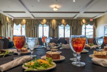 A table set for a meal in a dining room. Glasses of iced tea and food are on plates.